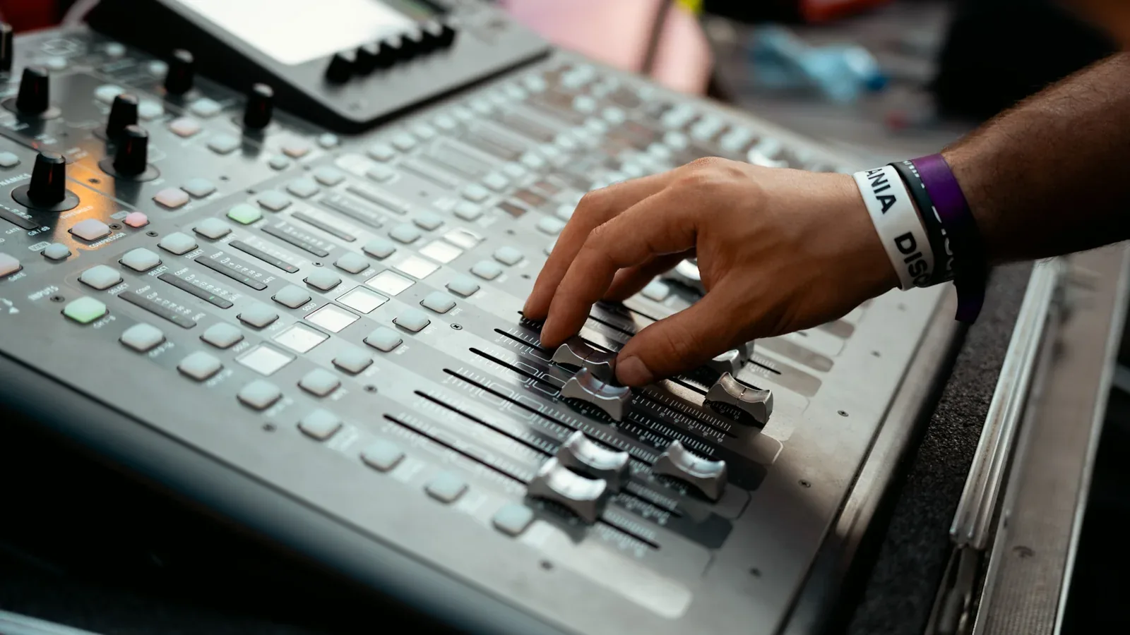 Una mano regola i fader del mixer audio